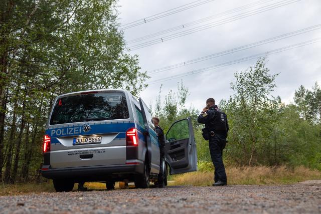 04 September 2026, Saxony, Schleife: Police officers are stationed in a wooded area beneath a power line near the town of Schleife in the Görlitz district. Following attempts to sabotage the power grid in other federal states, police have now also discovered "unknown explosive devices" in Saxony. Photo: Jürgen Lösel/dpa