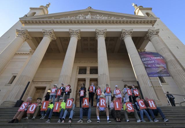 07 September 2026, Brandenburg, Potsdam: People form the phrase "We stand in solidarity" with their bodies on the steps of St. Nicholas Church in downtown Potsdam during a demonstration at the Old Market against the Alternative for Germany (AfD) electoral success in Saxony-Anhalt. Photo: Michael Bahlo/dpa