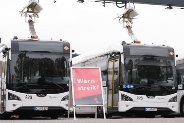 08 September 2026, Schleswig-Holstein, Kiel: A sign reading "Warning Strike" stands in front of buses parked in the KVG Kieler Transport company depot. The Verdi service workers' union has called for a warning strike in local public transportation in some cities. Photo: Marcus Brandt/dpa
