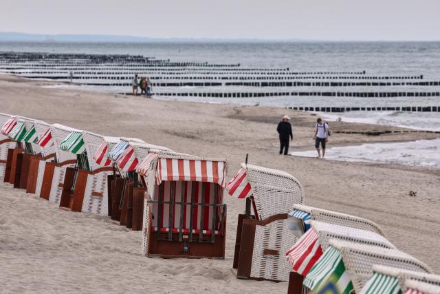 08 September 2026, Mecklenburg-Western Pomerania, Graal-Müritz: Only a few people walk past empty beach chairs along the Baltic Sea. Overcast late-summer weather prevails in northern Germany. Photo: Bernd Wüstneck/dpa