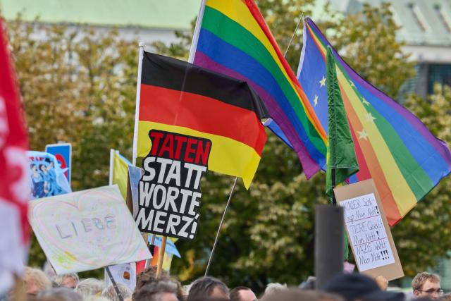 12 September 2026, Hamburg: A person holds up a banner on Jungfernstieg that reads, "Actions, not words, Merz" during the coalition demonstration against right-wing extremism and for democratic cohesion following the state election in Saxony-Anhalt. Photo: Georg Wendt/dpa