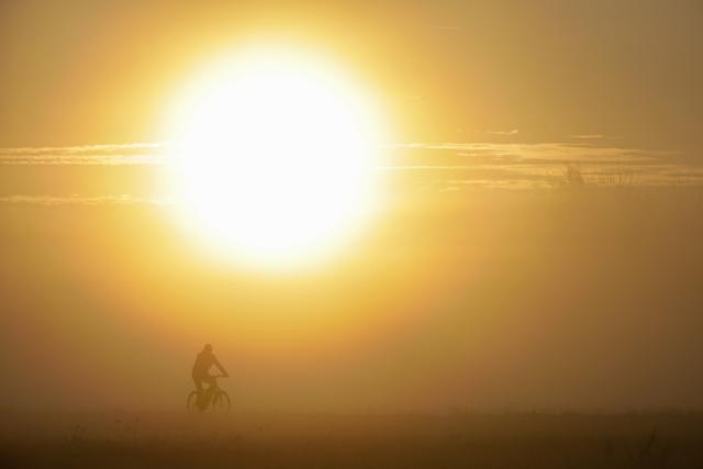 13 September 2026, Baden-Wuerttemberg, Riedlingen: A cyclist rides through the fog this morning, while the sun rises behind him. Photo: Thomas Warnack/dpa