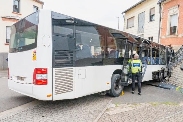 14 September 2026, Saarland, Voelklingen: A school bus is pictured after it collided with several cars and crashed into the wall of a house in the Geislautern neighborhood in Voelklingen. According to the police initial reports, several people were injured. Photo: Becker & Bredel/dpa