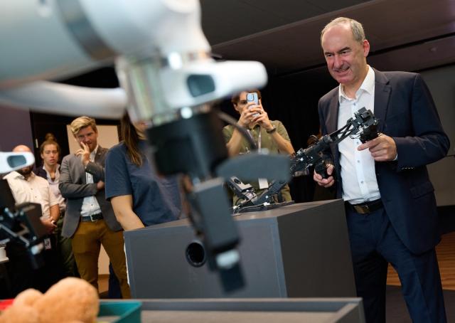 14 September 2026, Bavaria, Munich: Bavaria's Minister of Economic Affairs, operates an industrial robot during a press event at Agile Robots' corporate headquarters. Photo: Sven Hoppe/dpa