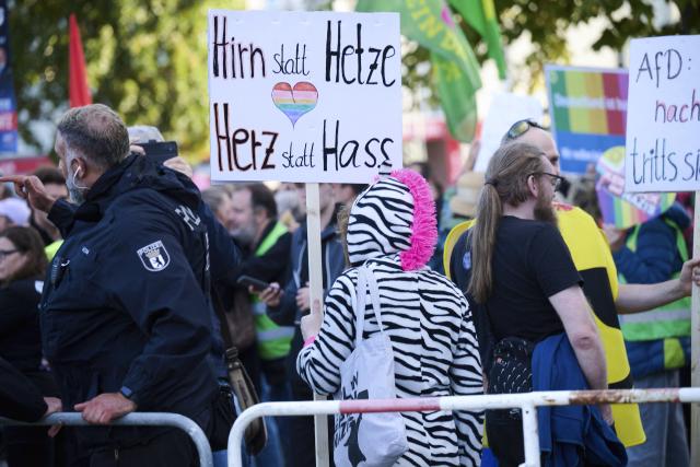 14 September 2026, Berlin: A demonstrator holds a sign reading "Use your brain instead of incitement, your heart instead of hate" in German during the counter-demonstration against the Alternative for Germany (AfD) rally on Hugenottenplatz. Photo: Annette Riedl/dpa