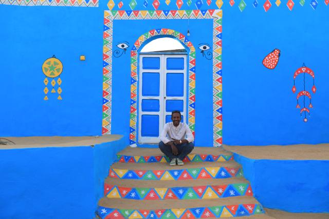 (241125) -- CAIRO, Nov. 25, 2024 (Xinhua) -- A Nubian man sits on the steps of a brightly-painted Nubian house at the Nubian village of Gharb Sohail in Aswan, Egypt, Nov. 24, 2024.
  Gharb Sohail, a Nubian village lying along the west bank of Nile, is a popular tourist destination in Aswan where visitors have the chance to know Nubian's unique cultures, traditions, crafts and food. (Xinhua/Sui Xiankai)