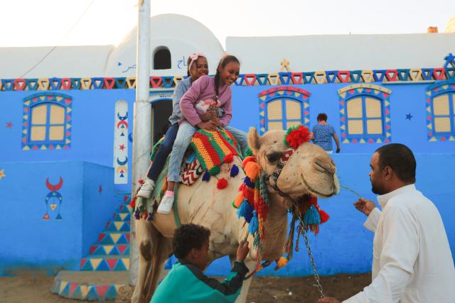 (241125) -- CAIRO, Nov. 25, 2024 (Xinhua) -- Children ride a camel at the Nubian village of Gharb Sohail in Aswan, Egypt, Nov. 24, 2024.
  Gharb Sohail, a Nubian village lying along the west bank of Nile, is a popular tourist destination in Aswan where visitors have the chance to know Nubian's unique cultures, traditions, crafts and food. (Xinhua/Sui Xiankai)