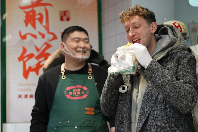 (241129) -- BEIJING, Nov. 29, 2024 (Xinhua) -- Evan Kail (R), a pawnshop manager from the United States, tries the local street food "Jianbing Guozi" in north China's Tianjin Municipality, Nov. 28, 2024.
  In 2022, Kail donated a photo album to China. The album features photos of Japanese atrocities in China during WWII. Two years after making this donation, Kail decided to embark on a month-long visit to China.
  Before he actually arrived in Beijing on Nov. 16, the news of Kail coming to China went viral on social media, with Chinese web users expressing their welcome and inviting him to different parts of the country to have a look.
  Kail started his trip in Beijing, and will also spend time in Tianjin, Shanghai and Nanjing -- where he plans to visit the Memorial Hall of the Victims in Nanjing Massacre by Japanese Invaders. (Xinhua/Li Ran)