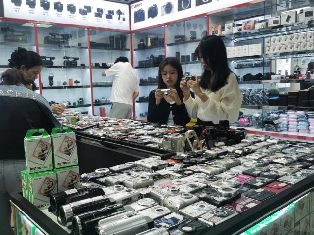 (241129) -- SHENZHEN, Nov. 29, 2024 (Xinhua) -- This photo taken with a mobile phone shows customers selecting CCD cameras at a store in China's famous electronics hub Huaqiangbei, in Shenzhen, south China's Guangdong Province, Nov. 5, 2024.
  TO GO WITH "Feature: Retro CCD cameras become hip new for young Chinese to document life" (Xinhua/Wang Feng)