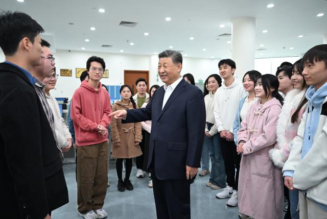 (241219) -- MACAO, Dec. 19, 2024 (Xinhua) -- Chinese President Xi Jinping, also general secretary of the Communist Party of China Central Committee and chairman of the Central Military Commission, talks with students in the library of Macau University of Science and Technology (MUST) in south China's Macao, Dec. 19, 2024. Xi, accompanied by Ho Iat Seng, chief executive of the Macao Special Administrative Region (SAR), visited the university Thursday morning. He talked with teachers, students and scientific researchers there. (Xinhua/Xie Huanchi)