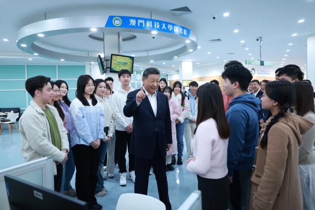 (241219) -- MACAO, Dec. 19, 2024 (Xinhua) -- Chinese President Xi Jinping, also general secretary of the Communist Party of China Central Committee and chairman of the Central Military Commission, talks with students in the library of Macau University of Science and Technology (MUST) in south China's Macao, Dec. 19, 2024. Xi, accompanied by Ho Iat Seng, chief executive of the Macao Special Administrative Region (SAR), visited the university Thursday morning. He talked with teachers, students and scientific researchers there. (Xinhua/Ju Peng)