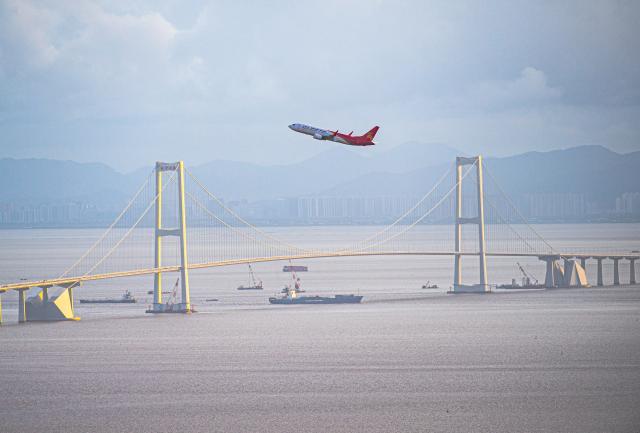 (241222) -- GUANGZHOU, Dec. 22, 2024 (Xinhua) -- An aircraft flies over the Shenzhong Bridge of the Shenzhen-Zhongshan Link in south China's Guangdong Province, June 23, 2024. (Xinhua/Mao Siqian)