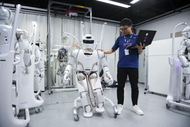 (241222) -- GUANGZHOU, Dec. 22, 2024 (Xinhua) -- A staff member conducts tests on a Walker X humanoid robot at a sci-tech company in Shenzhen, south China's Guangdong Province, June 26, 2024. (Xinhua/Mao Siqian)