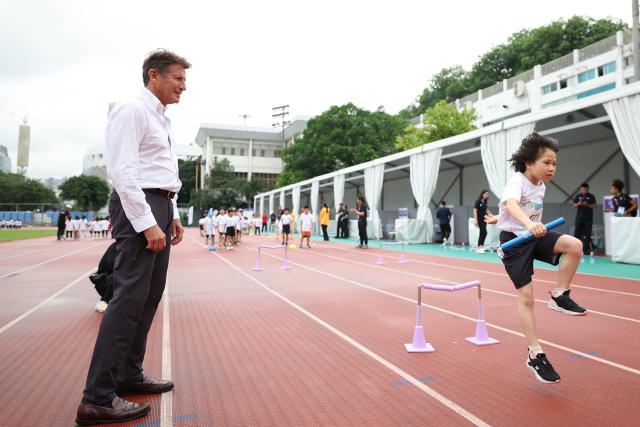 (250509) -- GUANGZHOU, May 9, 2025 (Xinhua) -- World Athletics president Sebastian Coe (L) looks at a local child in the Kids Athletics activities during the press conference before the World Athletics Relays Guangzhou 2025 in Guangzhou, south China's Guangdong Province, May 9, 2025. (Xinhua/Li Ming)