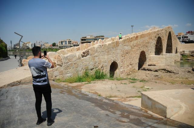 (250511) -- DOHUK, May 11, 2025 (Xinhua) -- A man takes photos of the ancient Dalal Bridge in Dohuk province, Iraq, May 10, 2025. The construction of Dalal Bridge dates back to the period of the Byzantine Empire. (Xinhua/Duan Minfu)