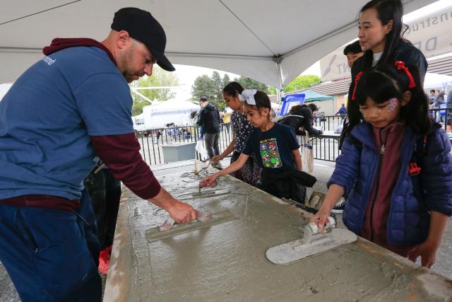 (250511) -- RICHMOND, May 11, 2025 (Xinhua) -- People try their hands at concrete paving during the Public Works Open House event in Richmond, British Columbia, Canada, May 10, 2025. Featuring interactive exhibits, equipment displays and more, the one-day event offered a behind-the-scenes look at the essential services that keep the city running smoothly. (Photo by Liang Sen/Xinhua)