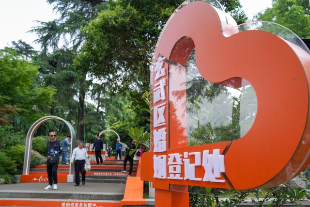 (250511) -- BEIJING, May 11, 2025 (Xinhua) -- People walk past an installation for a marriage registration office at the Xuanwu Lake Park in Nanjing, east China's Jiangsu Province, May 10, 2025. (Xinhua/Li Bo)