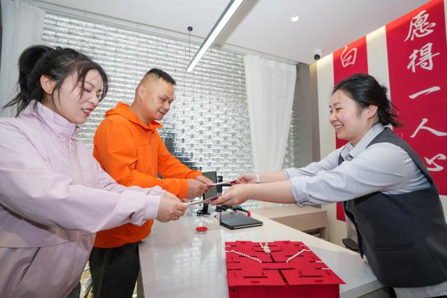 (250511) -- BEIJING, May 11, 2025 (Xinhua) -- A staff member hands marriage certificates to a couple at a marriage registration office in Nanjing, east China's Jiangsu Province, May 10, 2025. (Xinhua/Li Bo)
