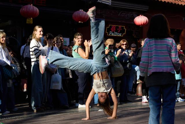 (250511) -- BUENOS AIRES, May 11, 2025 (Xinhua) -- People watch the performance of a street artist in the Chinatown in Buenos Aires, Argentina, May 10, 2025. In 2009, the archway of the Chinatown in Buenos Aires was officially completed. Nowadays, the Chinatown has become an important tourist attraction in the local area, attracting many people to experience the charm of Eastern culture. (Xinhua/Meng Dingbo)