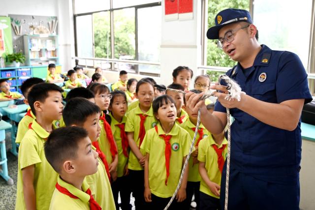 (250511) -- BEIJING, May 11, 2025 (Xinhua) -- A rescuer introduces the proper use of escape ropes to students at a primary school in Wuyi County, east China's Zhejiang Province, May 9, 2025. China observes the National Disaster Prevention and Reduction Day on May 12 each year. Various publicity, drill and training activities are carried out across China to improve public awareness in scientific disaster prevention and self-rescue. (Photo by Zhang Jiancheng/Xinhua)