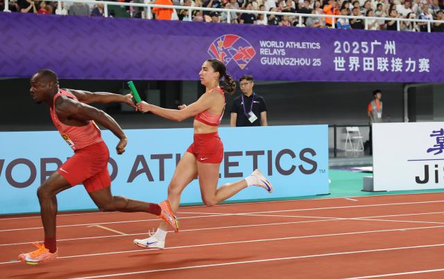 (250511) -- GUANGZHOU, May 11, 2025 (Xinhua) -- Marie-Eloise Leclair (R) of team Canada relays with teammate Duan Asemota during the mixed 4x100m relay final at the World Athletics Relays Guangzhou 2025 in Guangzhou, south China's Guangdong Province, May 11, 2025. (Xinhua/Li Ming)