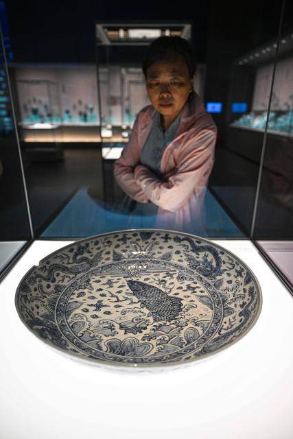 (250614) -- QIONGHAI, June 14, 2025 (Xinhua) -- A visitor looks at a plate displayed at the China (Hainan) Museum of the South China Sea in Qionghai, south China's Hainan Province, June 12, 2025. A great number of exhibits relevant to the Maritime Silk Road are showcased at the China (Hainan) Museum of the South China Sea, providing valuable insights into the prosperity of the Maritime Silk Road in ancient China and the exchanges between Chinese and foreign civilizations. (Xinhua/Pu Xiaoxu)