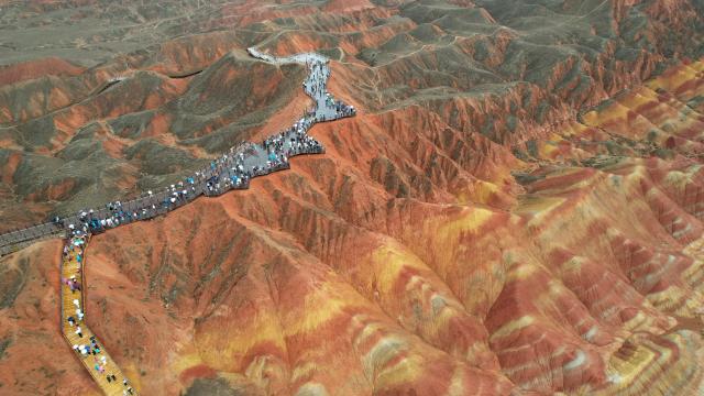 (250623) -- ZHANGYE, June 23, 2025 (Xinhua) -- An aerial drone photo taken on June 22, 2025 shows tourists enjoying the scenery of Danxia landform in the rain at the Danxia National Geological Park in Zhangye, northwest China's Gansu Province. (Xinhua/Chen Bin)