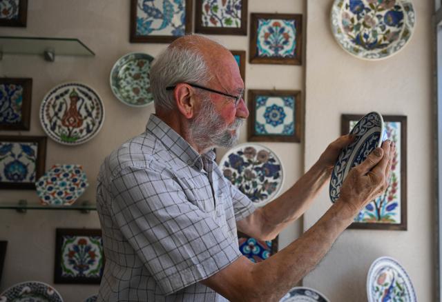 (250630) -- IZNIK (TÜRKIYE), June 30, 2025 (Xinhua) -- Master artisan Adil Can Guven looks at a blue and white porcelain plate at his studio in Iznik, Türkiye, on June 26, 2025. In the historic town of Iznik in northwestern Türkiye, renowned for its centuries-old ceramic tradition, master artisan Adil Can Guven is devoted to preserving and revitalizing this ancient craft. (Xinhua/Liu Lei) TO GO WITH Interview: Turkish master highlights enduring porcelain bond between Iznik, China