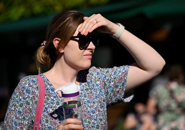 (250701) -- LONDON, July 1, 2025 (Xinhua) -- A woman blocks the sun with her hand on the opening day of the Wimbledon Championships in London, Britain, June 30, 2025. Tennis fans faced the hottest start to Wimbledon on record on Monday as temperature soared to 32 degrees Celsius. (Xinhua/Li Ying)
