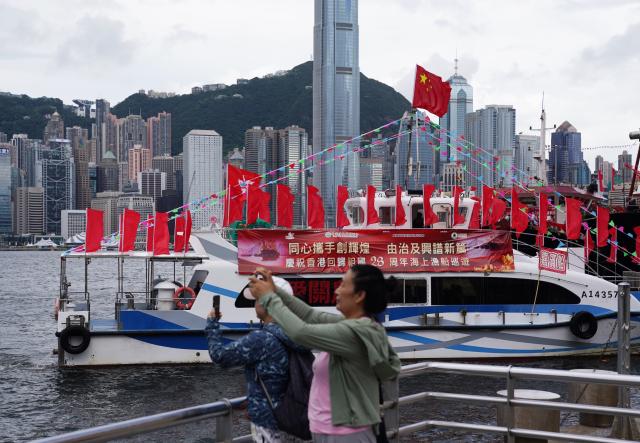(250701) -- HONG KONG, July 1, 2025 (Xinhua) -- Citizens take photos of cruising fishing vessels on the Tsim Sha Tsui waterfront in Hong Kong, south China, July 1, 2025. Fishing vessels take part in a cruise held by the Hong Kong Fishermen Consortium to celebrate the 28th anniversary of Hong Kong's return to the motherland at Victoria Harbour on Tuesday. (Xinhua/Wang Shen)