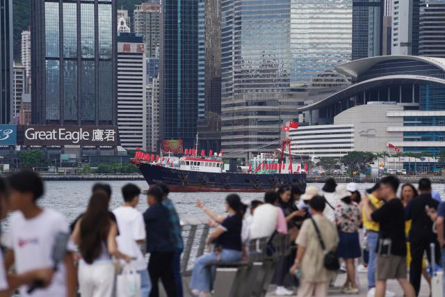 (250701) -- HONG KONG, July 1, 2025 (Xinhua) -- Citizens take photos of cruising fishing vessels on the Tsim Sha Tsui waterfront in Hong Kong, south China, July 1, 2025. Fishing vessels take part in a cruise held by the Hong Kong Fishermen Consortium to celebrate the 28th anniversary of Hong Kong's return to the motherland at Victoria Harbour on Tuesday. (Xinhua/Wang Shen)