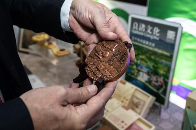 (250701) -- RIO DE JANEIRO, July 1, 2025 (Xinhua) -- A visitor holds a handicraft featuring the archaeological ruins of Liangzhu, a UNESCO World Heritage site, during an exposition of innovation in traditional craftsmanship of the east China's city of Hangzhou at Tiradentes Palace in Rio de Janeiro, Brazil, June 30, 2025. The event showcased a variety of Chinese traditional crafts and their innovative expressions to the Brazilian public through demonstrations and interactive experiences. (Xinhua/Wang Tiancong)