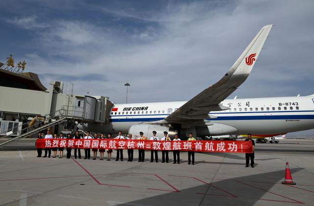 (250702) -- DUNHUANG, July 2, 2025 (Xinhua) -- The crew members of the inaugural direct flight from Hangzhou to Dunhuang operated by Air China pose for group photos with airport staff at Dunhuang Mogao International Airport in Dunhuang, northwest China's Gansu Province, July 1, 2025.
  The three new flight routes were launched here on Tuesday. (Photo by Zhang Xiaoliang/Xinhua)