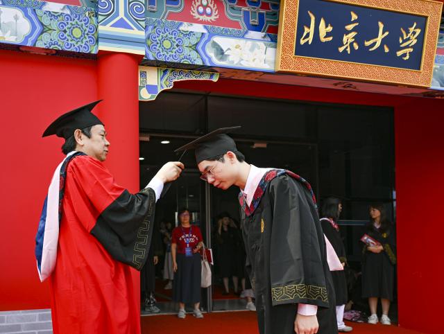 (250702) -- BEIJING, July 2, 2025 (Xinhua) -- Liu Qiao, dean of Peking University's Guanghua School of Management, turns the tassel for a graduate at Peking University in Beijing, capital of China, July 2, 2025. Peking University held the graduation ceremony on Wednesday and conferred bachelor's degrees to more than 4,000 graduates. (Xinhua/Chen Shuo)