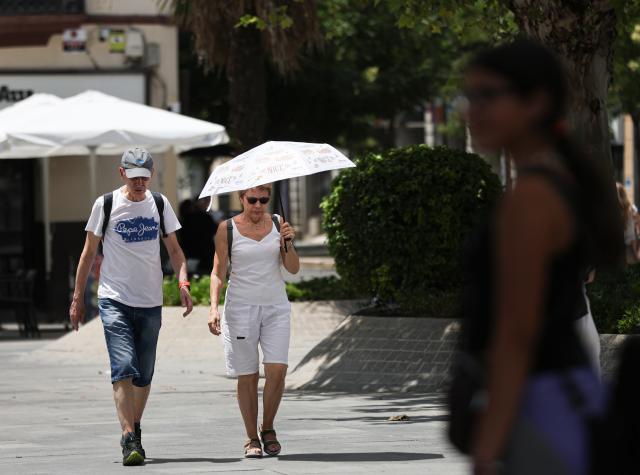 (250703) -- SEVILLE, July 3, 2025 (Xinhua) -- People walk with a parasol in Seville, Spain, July 2, 2025. Spain continues to endure a record-breaking heatwave. More than 100 monitoring stations of the Spanish meteorological agency AEMET registered temperatures exceeding 40 degrees Celsius during the first major heatwave of the year. (Xinhua/Li Jing)