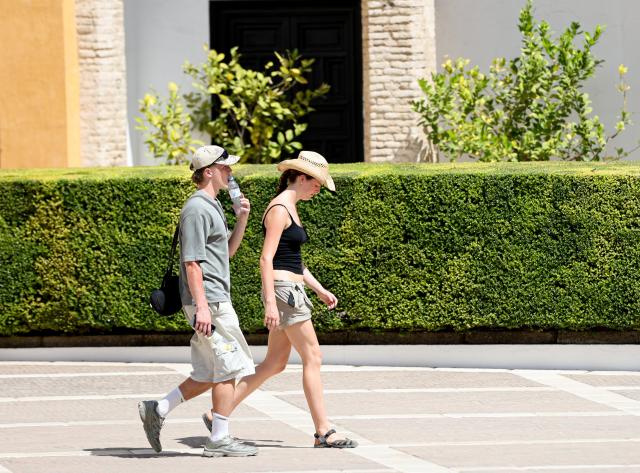 (250703) -- SEVILLE, July 3, 2025 (Xinhua) -- People walk amid the heatwave in Seville, Spain, July 2, 2025. Spain continues to endure a record-breaking heatwave. More than 100 monitoring stations of the Spanish meteorological agency AEMET registered temperatures exceeding 40 degrees Celsius during the first major heatwave of the year. (Xinhua/Li Jing)