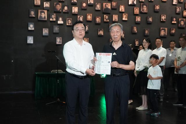(250703) -- NANJING, July 3, 2025 (Xinhua) -- Jiang Zhongrong (R), son of the Nanjing Massacre survivor Xie Guiying, donates an item belonging to Xie to the Memorial Hall of the Victims in Nanjing Massacre by Japanese Invaders in Nanjing, east China's Jiangsu Province, July 2, 2025. A "lights out" ceremony for two survivors of the Nanjing Massacre who passed away this year was held here on Wednesday. On a photo wall featuring survivors of the Nanjing Massacre, the lightboxes of Liu Guixiang and Xie Guiying were dimmed off, and their colored photos then turned to black and white.
   With the passing away of Liu and Xie earlier this year, the number of living registered survivors has decreased to 26. (Photo by Liu Zhenrui/Xinhua)