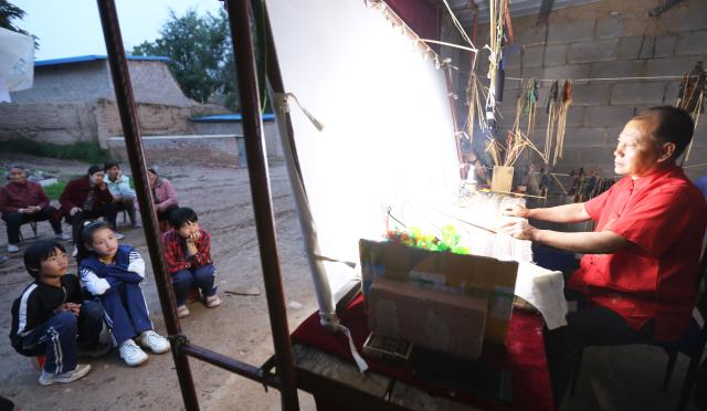 (250703) -- TONGWEI, July 3, 2025 (Xinhua) -- Liu Mancang performs a shadow puppet show in Changjiahe Town of Tongwei County, northwest China's Gansu Province, June 25, 2025. After harvesting his own wheat, Liu Mancang, an inheritor of the national intangible cultural heritage project Tongwei Shadow Puppetry, began traveling through the village to perform shadow play for his fellow villagers in Changjiahe Town, Tongwei County, making the most of his leisure time during the farming off season.
   Tongwei Shadow Puppetry is widely spread across Dingxi, Tianshui and Longnan in Gansu Province. It is a folk drama in which animal skins or cardboard are made into silhouettes to perform stories. 
   Liu, now 60, began to learn shadow puppetry from his grandfather at the age of 12. After decades of study, he has mastered the skills of shadow puppetry proficiently and collected and sorted out over a hundred shadow puppetry scripts. In 2018, he was recognized as an inheritor of Tongwei Shadow Puppetry.
   Liu has visited and studied in provinces like Shaanxi, Henan and Guangdong. While improving his own skills, he also promoted Tongwei Shadow Puppetry through voluntary performances in schools, hoping that this ancient folk art would shine with new luster. (Photo by Wang Kexian/Xinhua)