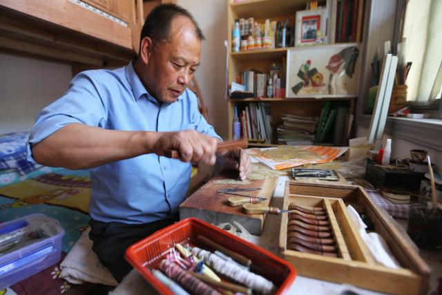 (250703) -- TONGWEI, July 3, 2025 (Xinhua) -- Liu Mancang carves on a shadow puppet at his home in Changjiahe Town of Tongwei County, northwest China's Gansu Province, June 25, 2025. After harvesting his own wheat, Liu Mancang, an inheritor of the national intangible cultural heritage project Tongwei Shadow Puppetry, began traveling through the village to perform shadow play for his fellow villagers in Changjiahe Town, Tongwei County, making the most of his leisure time during the farming off season.
   Tongwei Shadow Puppetry is widely spread across Dingxi, Tianshui and Longnan in Gansu Province. It is a folk drama in which animal skins or cardboard are made into silhouettes to perform stories. 
   Liu, now 60, began to learn shadow puppetry from his grandfather at the age of 12. After decades of study, he has mastered the skills of shadow puppetry proficiently and collected and sorted out over a hundred shadow puppetry scripts. In 2018, he was recognized as an inheritor of Tongwei Shadow Puppetry.
   Liu has visited and studied in provinces like Shaanxi, Henan and Guangdong. While improving his own skills, he also promoted Tongwei Shadow Puppetry through voluntary performances in schools, hoping that this ancient folk art would shine with new luster. (Photo by Wang Kexian/Xinhua)