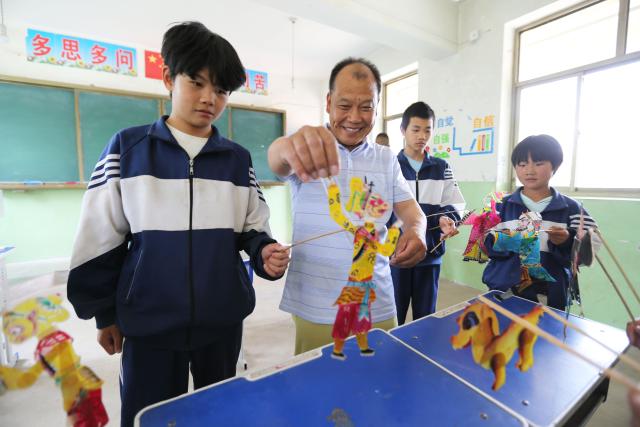 (250703) -- TONGWEI, July 3, 2025 (Xinhua) -- Liu Mancang instructs students to play shadow puppets in Changjiahe Town of Tongwei County, northwest China's Gansu Province, July 1, 2025. After harvesting his own wheat, Liu Mancang, an inheritor of the national intangible cultural heritage project Tongwei Shadow Puppetry, began traveling through the village to perform shadow play for his fellow villagers in Changjiahe Town, Tongwei County, making the most of his leisure time during the farming off season.
   Tongwei Shadow Puppetry is widely spread across Dingxi, Tianshui and Longnan in Gansu Province. It is a folk drama in which animal skins or cardboard are made into silhouettes to perform stories. 
   Liu, now 60, began to learn shadow puppetry from his grandfather at the age of 12. After decades of study, he has mastered the skills of shadow puppetry proficiently and collected and sorted out over a hundred shadow puppetry scripts. In 2018, he was recognized as an inheritor of Tongwei Shadow Puppetry.
   Liu has visited and studied in provinces like Shaanxi, Henan and Guangdong. While improving his own skills, he also promoted Tongwei Shadow Puppetry through voluntary performances in schools, hoping that this ancient folk art would shine with new luster. (Photo by Wang Kexian/Xinhua)
