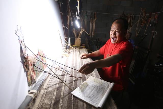 (250703) -- TONGWEI, July 3, 2025 (Xinhua) -- Liu Mancang performs shadow puppet show in Changjiahe Town of Tongwei County, northwest China's Gansu Province, June 25, 2025. After harvesting his own wheat, Liu Mancang, an inheritor of the national intangible cultural heritage project Tongwei Shadow Puppetry, began traveling through the village to perform shadow play for his fellow villagers in Changjiahe Town, Tongwei County, making the most of his leisure time during the farming off season.
   Tongwei Shadow Puppetry is widely spread across Dingxi, Tianshui and Longnan in Gansu Province. It is a folk drama in which animal skins or cardboard are made into silhouettes to perform stories. 
   Liu, now 60, began to learn shadow puppetry from his grandfather at the age of 12. After decades of study, he has mastered the skills of shadow puppetry proficiently and collected and sorted out over a hundred shadow puppetry scripts. In 2018, he was recognized as an inheritor of Tongwei Shadow Puppetry.
   Liu has visited and studied in provinces like Shaanxi, Henan and Guangdong. While improving his own skills, he also promoted Tongwei Shadow Puppetry through voluntary performances in schools, hoping that this ancient folk art would shine with new luster. (Photo by Wang Kexian/Xinhua)