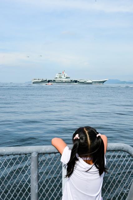 (250703) -- HONG KONG, July 3, 2025 (Xinhua) -- A girl watches as the aircraft carrier Shandong arrives in Hong Kong waters, south China, July 3, 2025. A fleet of the Chinese People's Liberation Army (PLA) Navy led by the aircraft carrier Shandong arrived in the Hong Kong Special Administrative Region (HKSAR) on Thursday morning, kicking off a five-day visit.
   The aircraft carrier and the Yan'an missile destroyer were anchored near the west end of the Victoria Harbor, while the Zhanjiang missile destroyer and the Yuncheng missile frigate docked at the PLA Hong Kong Garrison's naval base in Stonecutters Island.
   This is the Shandong's first visit to Hong Kong. From Friday to Sunday, the Shandong, the Zhanjiang and the Yuncheng will host open tours, lectures, drill demonstrations and other exchange activities. (Xinhua/Zhu Wei)