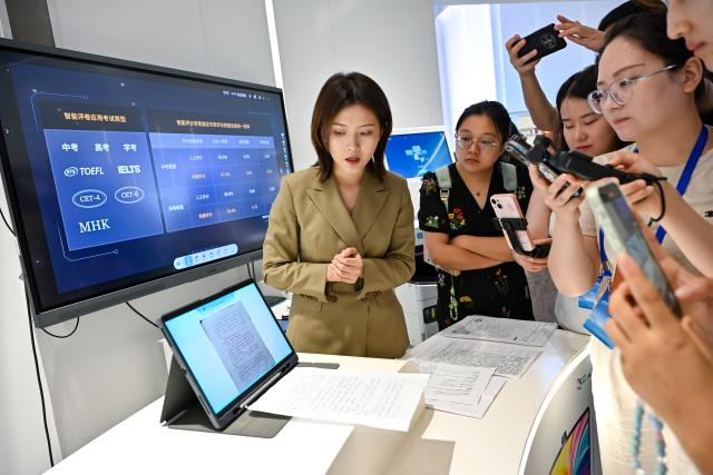(250703) -- HEFEI, July 3, 2025 (Xinhua) -- A staff member introduces the homework correction function of an AI-powered learning machine at the artificial intelligence experience hall of iFLYTEK in Hefei, east China's Anhui Province, July 2, 2025. In alignment with the national strategy to cultivate industries of the future, Hefei is forging ahead with strategic layouts in emerging frontiers like quantum information, low-altitude economy, commercial aerospace, fusion energy, artificial intelligence, intelligent robotics, and biosynthetic manufacturing to accelerate industrial cluster formation. The city has achieved remarkable progress across multiple future industry sectors, emerging as a robust hub of rapid advancement. (Xinhua/Zhang Cheng)