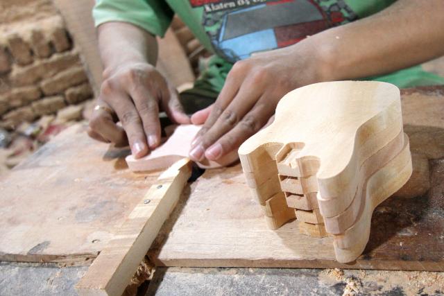 (250703) -- KLATEN, July 3, 2025 (Xinhua) -- A worker makes miniature guitars at a handicraft workshop in Klaten Regency, Central Java, Indonesia, on July 3, 2025. Those miniature guitars are made from mahogany, aluminum, fiber, resin and strings. (Photo by Bram Selo/Xinhua)
