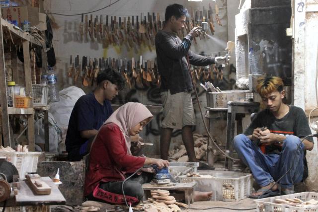 (250703) -- KLATEN, July 3, 2025 (Xinhua) -- Workers make miniature guitars at a handicraft workshop in Klaten Regency, Central Java, Indonesia, on July 3, 2025. Those miniature guitars are made from mahogany, aluminum, fiber, resin and strings. (Photo by Bram Selo/Xinhua)