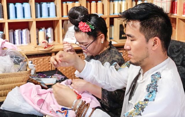 (250704) -- GUIYANG, July 4, 2025 (Xinhua) -- Yang Chunlin (R) makes embroidery at his studio in Kaili, southwest China's Guizhou Province, May 14, 2025. (Xinhua/Zhou Xuanni)