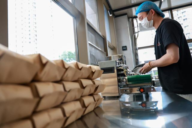 (250704) -- GUIYANG, July 4, 2025 (Xinhua) -- A shop assistant packs coffee beans at a coffee shop in Guiyang, southwest China's Guizhou Province, June 9, 2025.
  Guiyang has made a name for itself as a coffee powerhouse despite having no coffee farms. Home to more than 3,000 coffee shops, the provincial capital has produced over 10 world and national champions in coffee roasting. Thanks to its vibrant coffee culture, Guiyang is not only drawing a surge of coffee lovers but also boosting youth employment and energizing the local economy. (Xinhua/Liu Xu)
