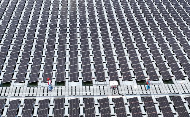 (250704) -- QINGDAO, July 4, 2025 (Xinhua) -- An aerial drone photo taken on July 4, 2025 shows workers inspecting at the site of an floating offshore photovoltaic (PV) project of Sinopec Qingdao Refining & Chemical Co., Ltd. in Qingdao, east China's Shandong Province. The project was connected to the grid for electricity generation recently. Located in the Xihai'an (West Coast) New Area of the east China's coastal city, the project innovatively adopts a floating structure, with the photovoltaic panels rising and falling close to the water surface with the tide, and uses seawater to efficiently dissipate heat to improve power generation efficiency. With an installed capacity of 7.5 megawatts, it is expected to generate nearly 10 million kilowatt-hours of green electricity annually and reduce carbon dioxide emissions by 8,300 tons. Since it was put into use on July 1, the project has generated a total of 123,100 kilowatt-hours of electricity. (Photo by Zhang Jingang/Xinhua)