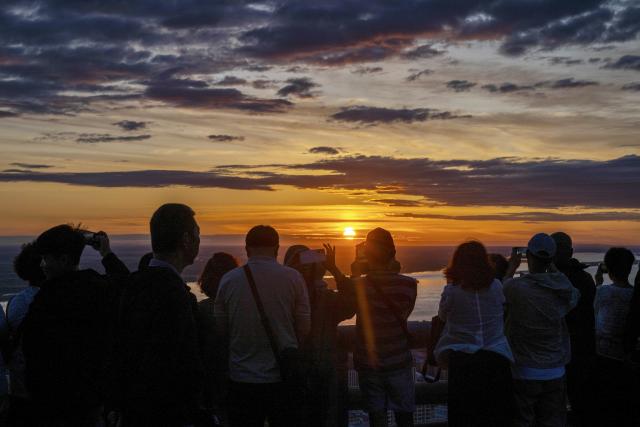 (250704) -- BEIJING, July 4, 2025 (Xinhua) -- Tourists take photos of the rising sun at Dongji Pavilion in Fuyuan City, northeast China's Heilongjiang Province, July 4, 2025. The Earth passed the aphelion on July 4, which is the time of year when the Earth is farthest from the sun, and the apparent diameter of the sun is the smallest in the year. (Xinhua/Zhang Tao)