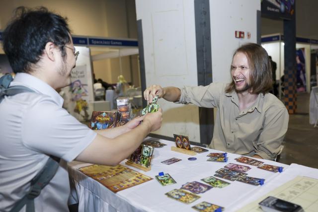 (250704) -- SHANGHAI, July 4, 2025 (Xinhua) -- An exhibitor from Russia demonstrates a self-designed card game during the China International Cartoon & Game Expo 2025 (CCG Expo 2025) in east China's Shanghai, July 4, 2025. The CCG Expo 2025 kicked off Friday at the Shanghai Convention and Exhibition Center of International Sourcing with the participation of 480 domestic and international exhibitors. The event will last until July 6. (Xinhua/Wang Xiang)
